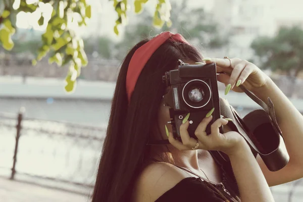 Asiática chica con cámara en el parque en la hora de la puesta del sol. Chica morena con cámara de cine en el color vintage — Foto de Stock