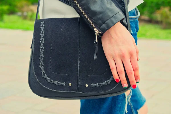 Jovem seguram yoyr mão sobre a bolsa preta em seu ombro vestindo jeans rasgado — Fotografia de Stock