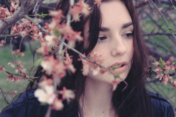 Sad girl hiding in cherry flower branches — Stock Photo, Image