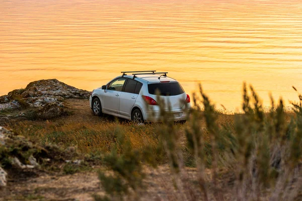Unrecognisable car parked on seashore at dawn — Stock Photo, Image