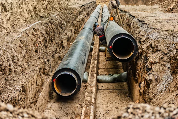 Wasserrohre im Erdgraben während der Reparaturarbeiten an den Sanitäranlagen. U-Bahn-Rohr wird im Graben fixiert — Stockfoto