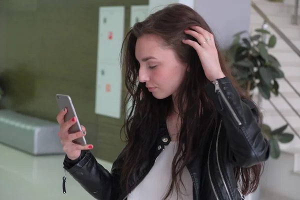 Jong meisje het lezen van tekstbericht in app tijdens het toching haar lange bruine haren — Stockfoto