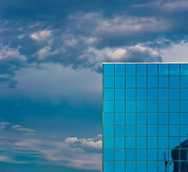 Wolkenkrabber, betegelde ramen en dramatische bewolkte hemel — Stockfoto