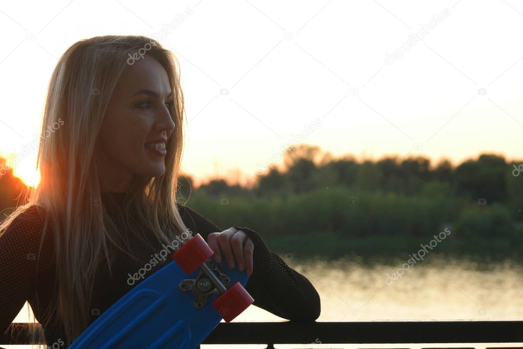 Blond hair woman posing in front of sunset on waterfront with a lot of copyspace
