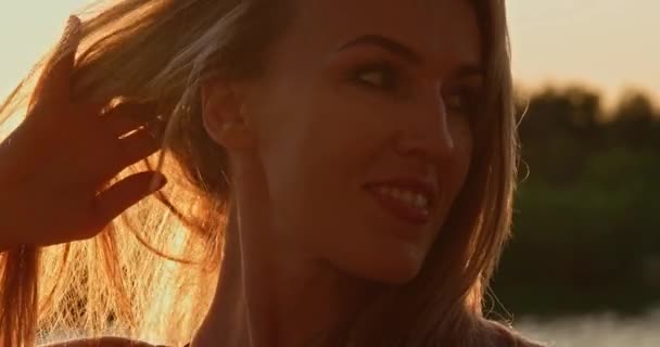 Взрослая женщина играет со своими светлыми волосами в подсветке — стоковое видео