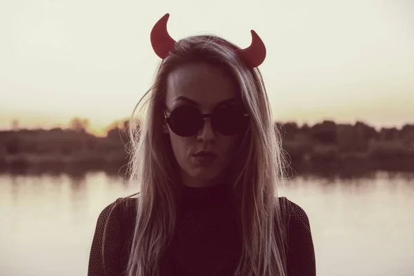 Femme mortellement sérieuse portant des lunettes de soleil et des cornes de diables — Photo