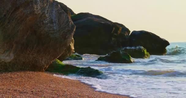 Riesige Felsbrocken an der Küste mit Wellen, die darauf brechen, Kippschuss — Stockvideo