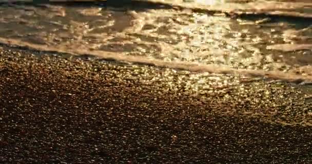 Las olas del mar lamiendo la playa en la luz dorada del atardecer — Vídeos de Stock