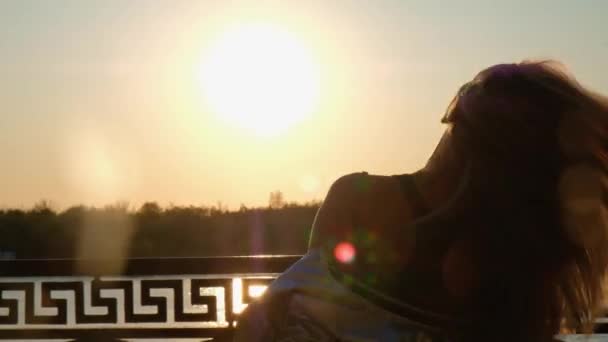 Вид ззаду щаслива блондинка волохата дівчина тремтить головою під час заходу сонця — стокове відео