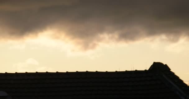 황혼에 지붕 위를 날고 있는 구름이 4K 에 어둠 이 내리고 있습니다 — 비디오