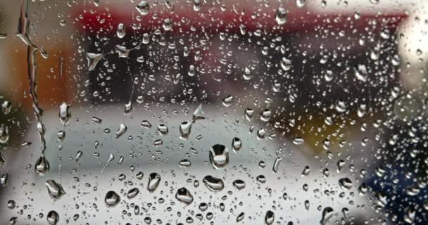 Aguas pluviales en el panel de cristal de la ventana en temporada lluviosa. Enfoque selectivo. Agua de las gotas de lluvia que se rompen en la superficie exterior de la ventana al verter lluvia. — Vídeo de stock