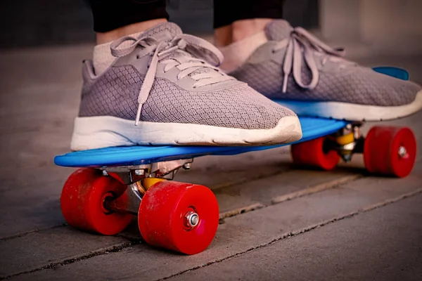 Het meisje vermoeide oude sneakers staat op skteboard — Stockfoto