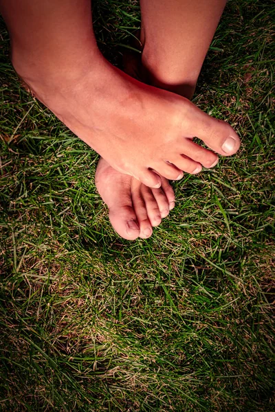 Feet in grass on meadow crossed over each other — Stock Photo, Image