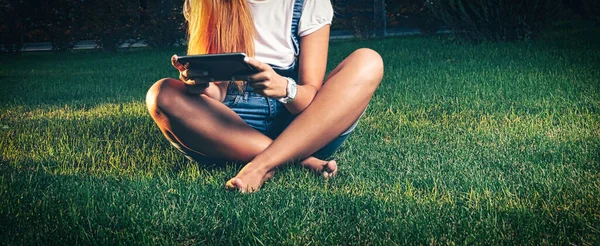 Studente in park e-learning op tablet PC zit cross-legged op het gras — Stockfoto