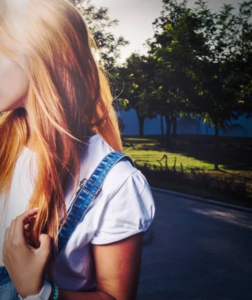 Блондинка с длинными волосами, позирующая в парке, смотрит в сторону, лица нет. — стоковое фото