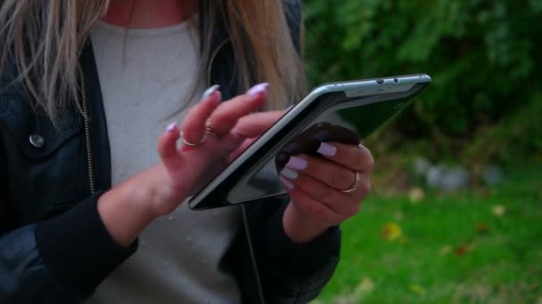 Žena pomocí svého tabletu PC v parku, textové zprávy nebo pomocí webové aplikace — Stock video