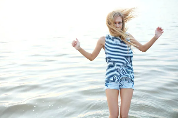 ブロンドの髪の女性は水の中に立っている 彼女の髪は風に吹かれ 左側のコピースペース — ストック写真