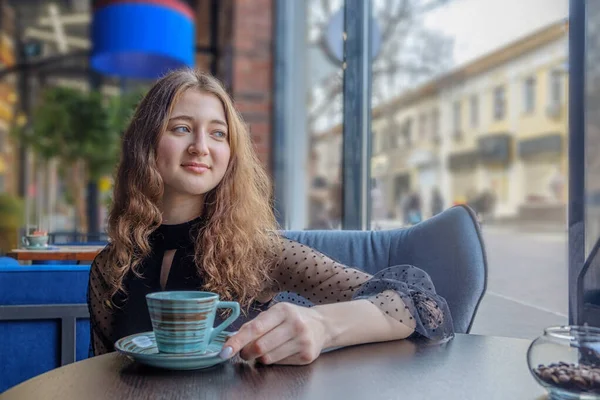 Het Roodharige Meisje Met Golvend Haar Zit Aan Een Tafel — Stockfoto