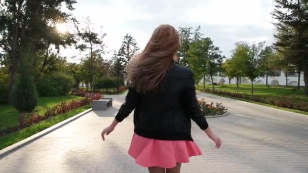Шикарная девушка в розовой юбке в замедленной съемке разворачивается в парке — стоковое видео