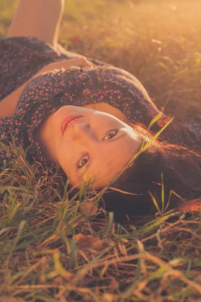 Chica feliz está acostado y mirando a la cámara en la hierba otoñal — Foto de Stock