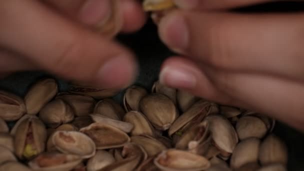 Een man reinigt pistachenoten van hun huid en gooit ze terug.. — Stockvideo
