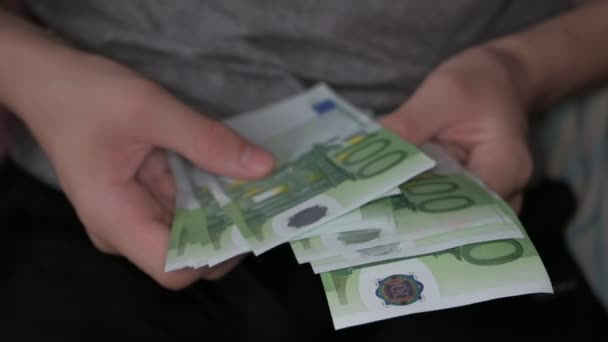 Ein Junge hält ein Bündel 100-Euro-Banknoten in den Händen und kontrolliert es — Stockvideo