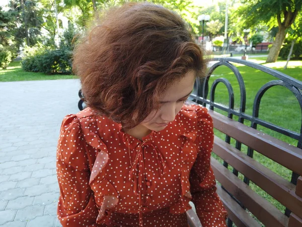 Mujer asiática sentada en el banco mirando hacia abajo. Mujer multicultural bastante joven disfrutando del verano en el parque en el banco de parques. —  Fotos de Stock