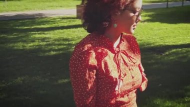 Eski moda elbiseli genç bir kız parkın yeşil çimlerinde dans ediyor.