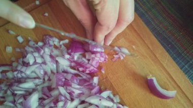 POV Kadını tahta kesme tahtasındaki soğanı testere bıçağıyla kesiyor..