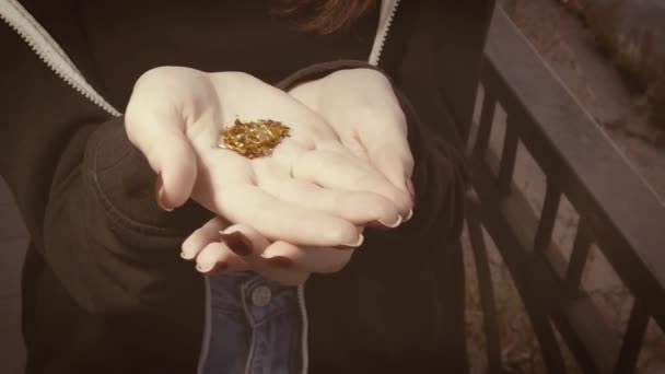 Dívka pózuje s hromadou zlatých částic na své dlani — Stock video