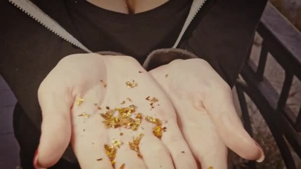 La ragazza mostra un mucchio di particelle d'oro sul palmo della mano e poi vengono trasportate dal vento — Video Stock