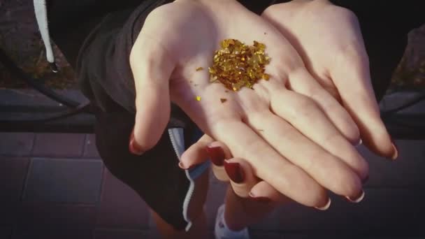 Dívka odfoukla zlaté částečky z dlaně. — Stock video