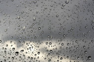 Su damlaları bir pencere camına yağmurlu bir gün