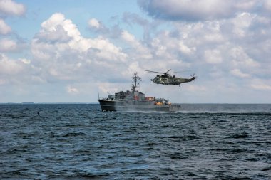 Helikopter kurtarma görevi denizde zor fırtınalı havalarda. NATO askeri helikopter ve gemi Baltık Denizi, Letonya; NATO askeri helikopter ve Baltık Denizi içinde eğitim gemi. NATO kurtarma görevi içinde gemi ve helikopter denize sıfır.