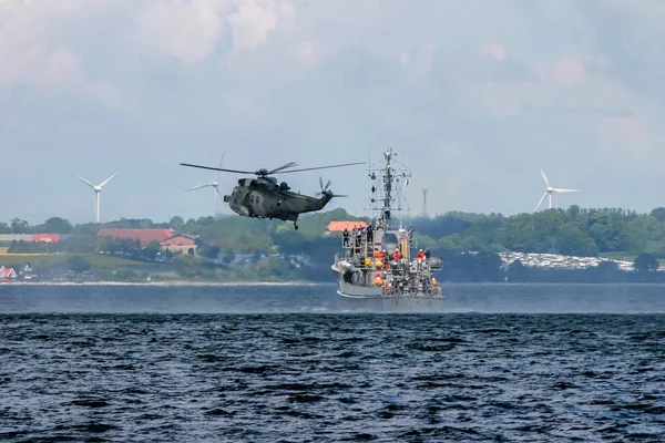 Helicopter rescue mission in difficult stormy weather at sea. NATO military helicopter and ship in Baltic sea, Latvia; NATO army helicopter and ship training in Baltic sea. NATO rescue mission in sea with ship and helicopter.