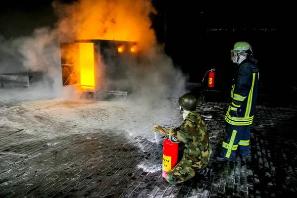 Firefighters training for fire fighting in Germany. Firefighter in fire protection suit spraying water to fire with smoke. Firefighter fighting fire attack, during training exercise