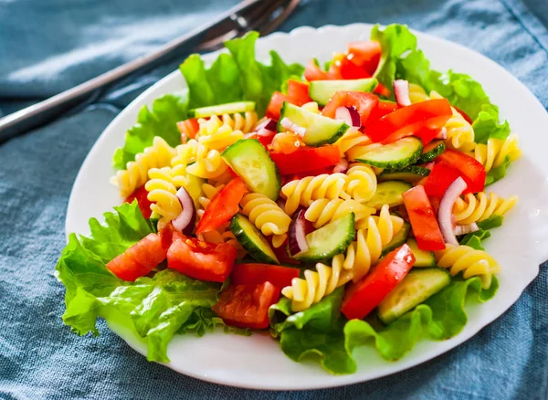 vegetables Pasta salad with tomato, lettuce, onion and cucumber in white plate on table