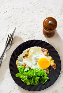 pastırma ve beyaz masa üzerinde siyah plaka salata ile kızarmış yumurta