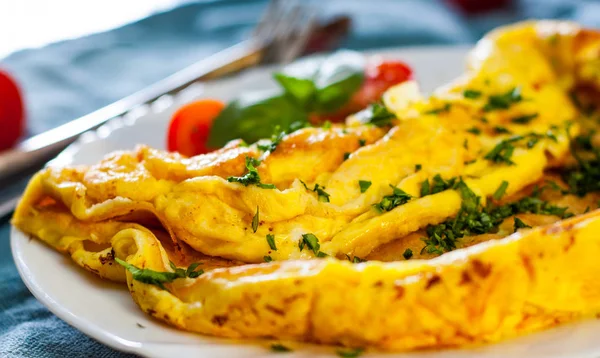 ahşap masa üzerinde beyaz bir tabak içinde omlet