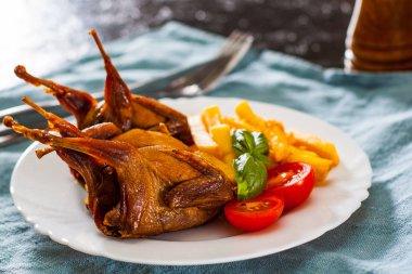 Kavrulmuş bıldırcınlar ve patates tablo beyaz bir tabakta servis