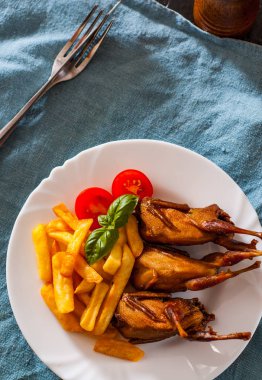 Kavrulmuş bıldırcınlar ve patates tablo beyaz bir tabakta servis