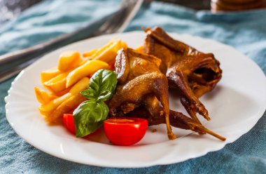 Kavrulmuş bıldırcınlar ve patates tablo beyaz bir tabakta servis