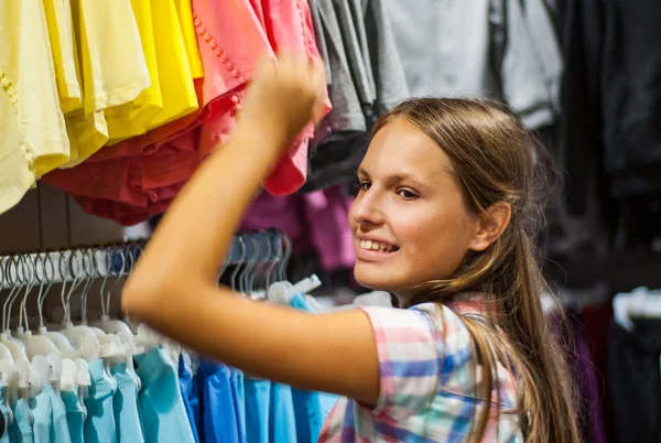 Teenage girl shopping for clothes inside Clothing store at shopping center