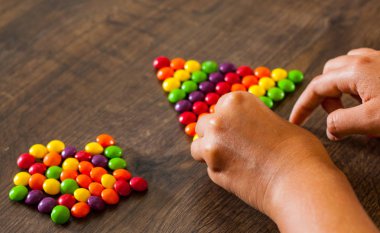 kadın eli bile renkli şekerler sırasının bir ahşap arka plan üzerinde toplar.