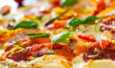 Pizza Mozzarella peyniri, jambon, domates, salam, biber, biber baharat ve taze fesleğen. İtalyan pizza. Yakın çekim.