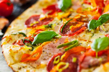 Pizza Mozzarella peyniri, jambon, domates, salam, biber, biber baharat ve taze fesleğen. İtalyan pizza. Yakın çekim.