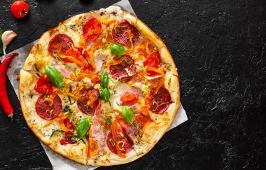 Pizza Mozzarella peyniri, jambon, domates, salam, biber, biber baharat ve taze fesleğen. İtalyan pizza.on siyah arka plan. kopya alanı ile. üstten görünüm