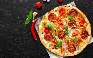 Pizza Mozzarella peyniri, jambon, domates, salam, biber, biber baharat ve taze fesleğen. İtalyan pizza.on siyah arka plan. kopya alanı ile. üstten görünüm