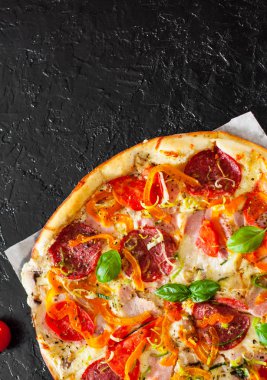 Pizza Mozzarella peyniri, jambon, domates, salam, biber, biber baharat ve taze fesleğen. İtalyan pizza.on siyah arka plan. kopya alanı ile. üstten görünüm