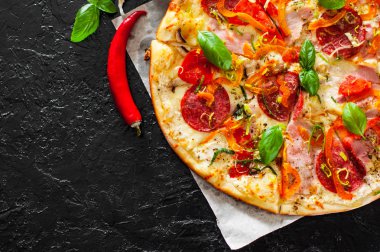 Pizza Mozzarella peyniri, jambon, domates, salam, biber, biber baharat ve taze fesleğen. İtalyan pizza.on siyah arka plan. kopya alanı ile. üstten görünüm